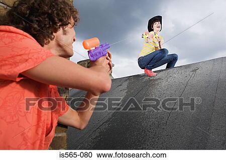 Couple playing with water pistols View Large Photo Image Stock Image - Couple playing with water pistols. Fotosearch