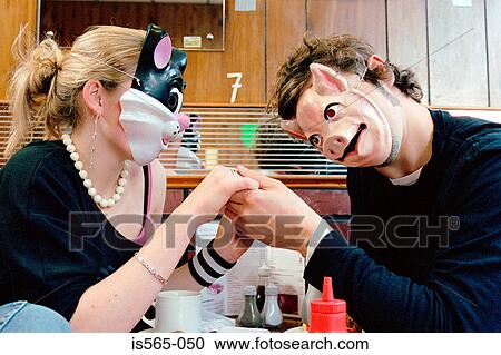 Stock Image - Couple wearing face masks in cafe. Fotosearch