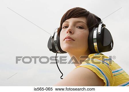 Stock Photography - Young woman listening to music on roof. Fotosearch