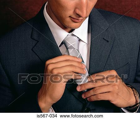 Businessman adjusting his tie View Large Photo Image Picture - Businessman adjusting his tie. Fotosearch