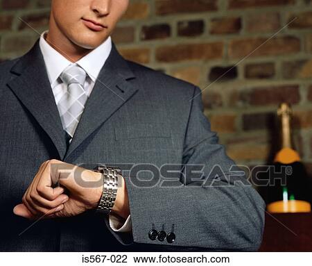Stock Image - Businessman looking at his watch. Fotosearch