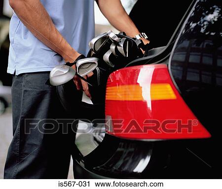 Man putting golf clubs in car boot View Large Photo Image Stock Image - Man putting golf clubs in car boot. Fotosearch