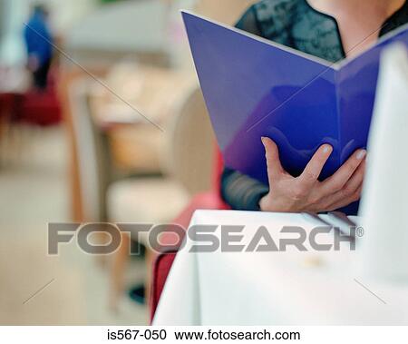 Stock Image - Woman reading menu in restaurant. Fotosearch