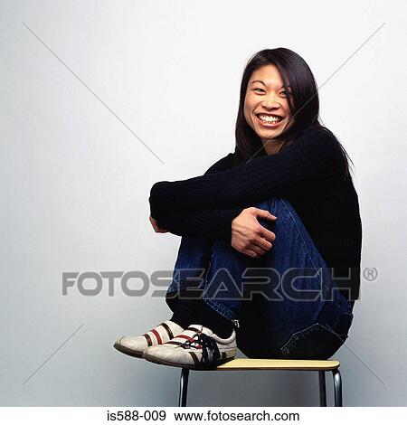 Stock Photo - Smiling woman on stool. Fotosearch