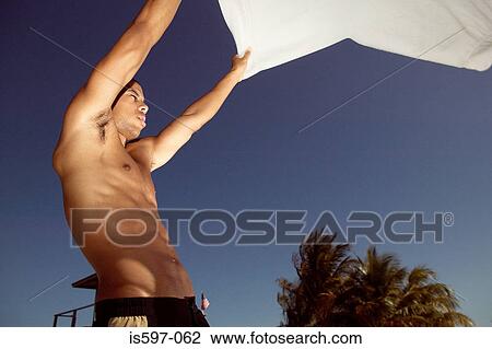 Man holding towel on beach View Large Photo Image Stock Image - Man holding towel on beach. Fotosearch