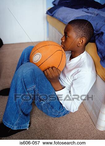 Stock Photo - Boy holding basketball in bedroom. Fotosearch