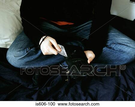 Stock Image - Boy holding wallet in bedroom. Fotosearch