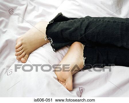Stock Image - Girl's barefeet on bed. Fotosearch