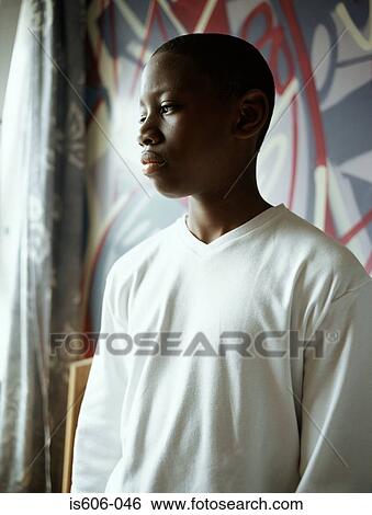 Stock Photograph - Teenage boy standing in bedroom. Fotosearch