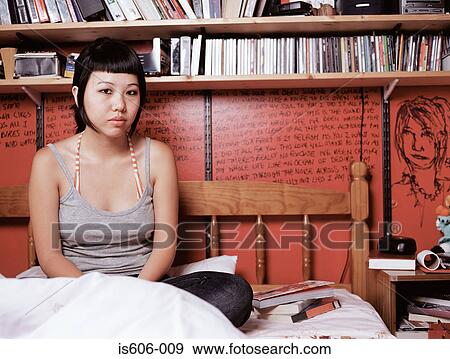Stock Photo - Teenage girl sitting on bed. Fotosearch