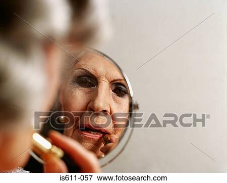 Close-up reflection of senior woman applying lipstick View Large Photo Image Stock Photo - Close-up reflection of senior woman applying lipstick . Fotosearch