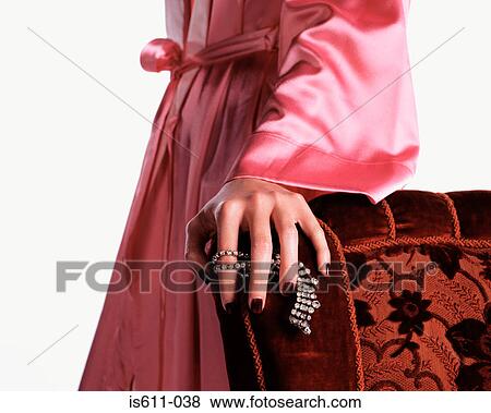 Woman holding necklace against chair View Large Photo Image Stock Photo - Woman holding necklace against chair. Fotosearch