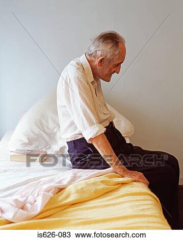 Stock Image - Elderly man sitting on his bed. Fotosearch