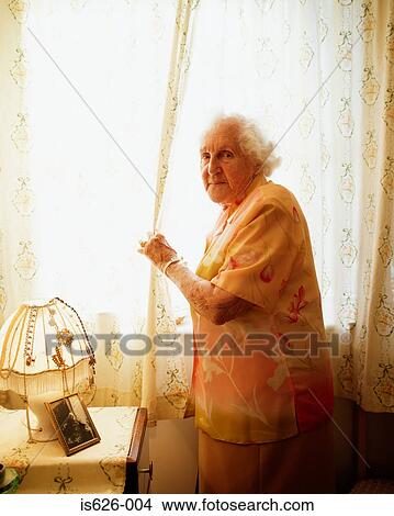 Elderly woman opening curtain View Large Photo Image Picture - Elderly woman opening curtain. Fotosearch