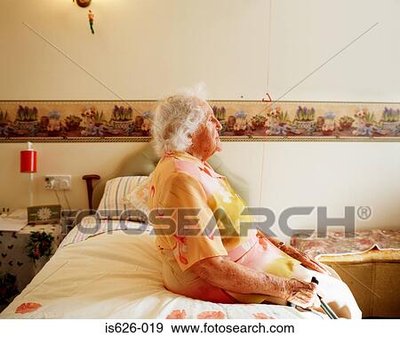 Elderly woman sitting on her bed View Large Photo Image Stock Photo - Elderly woman sitting on her bed . Fotosearch