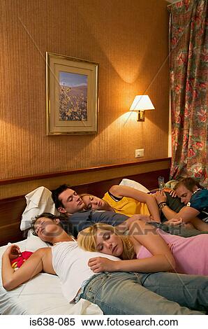 Stock Photography - Friends asleep on hotel bed . Fotosearch
