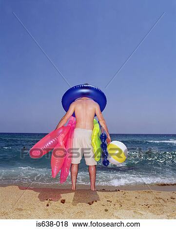 Man carrying inflatable toys View Large Photo Image Stock Photo - Man carrying inflatable toys. Fotosearch