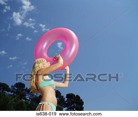 Stock Photo - Woman inflating a pink ring. Fotosearch