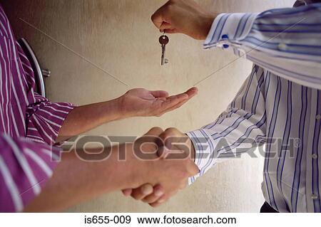 Handing over keys and shaking hands View Large Photo Image Stock Photo - Handing over keys and shaking hands. Fotosearch