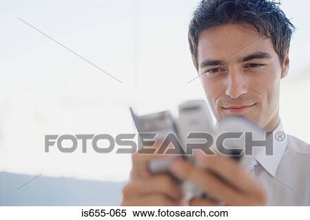 Man choosing between mobile phones View Large Photo Image Stock Photography - Man choosing between mobile phones. Fotosearch