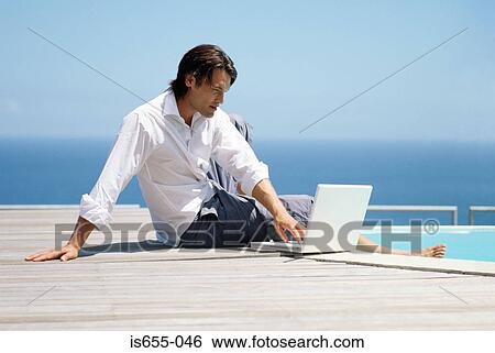 Man with laptop by swimming pool View Large Photo Image Stock Photograph - Man with laptop by swimming pool. Fotosearch