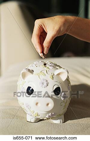 Putting money in a piggy bank View Large Photo Image Stock Image - Putting money in a piggy bank. Fotosearch