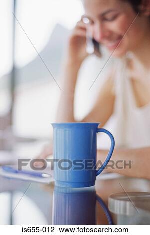 Stock Image - Woman on mobile phone with coffee cup. Fotosearch