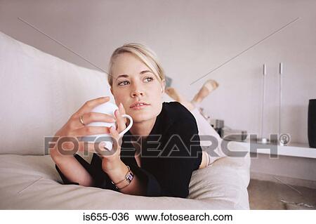 Woman relaxing on the sofa with a drink View Large Photo Image Stock Photograph - Woman relaxing on the sofa with a drink. Fotosearch