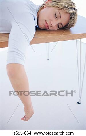 Picture - Woman sleeping on a desk. Fotosearch