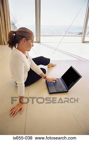 Woman using laptop on living room floor View Large Photo Image Stock Photo - Woman using laptop on living room floor. Fotosearch