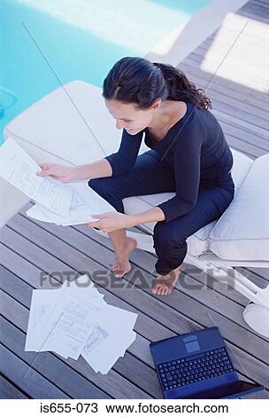 Stock Image - Woman working by the pool. Fotosearch