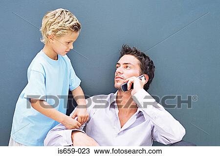 Stock Image - Boy trying to get father's attention. Fotosearch