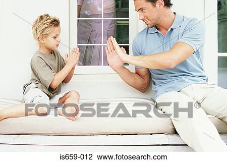 Stock Image - Father and son playing hand clapping game. Fotosearch