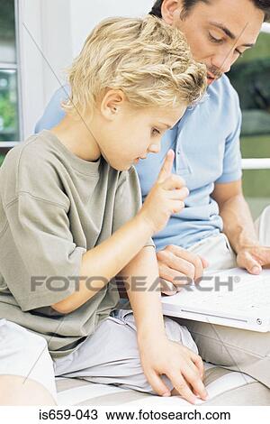 Stock Image - Father showing son how to use laptop. Fotosearch