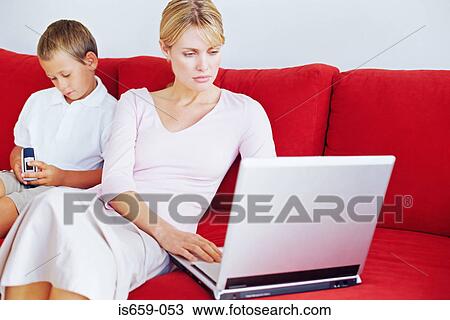 Mother and son using laptop and mobile phone View Large Photo Image Stock Image - Mother and son using laptop and mobile phone. Fotosearch