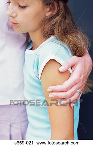 Stock Image - Sad looking girl with hand on her shoulder. Fotosearch