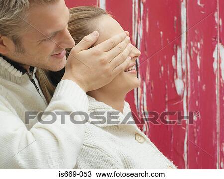 Stock Image - Man covering girlfriend's eyes. Fotosearch