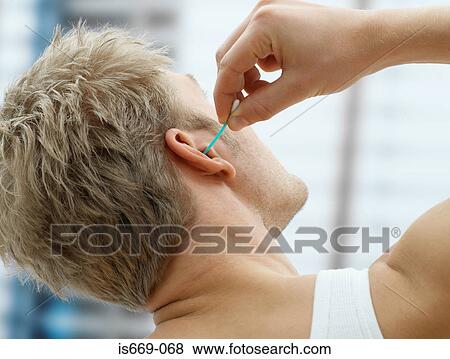 Stock Photo - Man putting cotton bud in his ear. Fotosearch