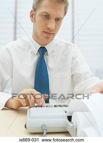 Stock Image - Man using calculator. Fotosearch