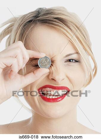 Stock Photo - Woman holding Euro coin to her eye. Fotosearch