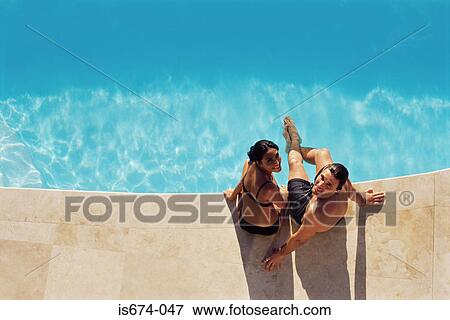 Couple sitting on the edge of swimming pool View Large Photo Image Stock Photo - Couple sitting on the edge of swimming pool. Fotosearch