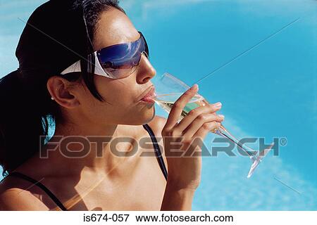 Stock Photo - Woman drinking champagne by the pool. Fotosearch