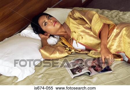 Woman lying on bed with magazine View Large Photo Image Stock Photography - Woman lying on bed with magazine. Fotosearch