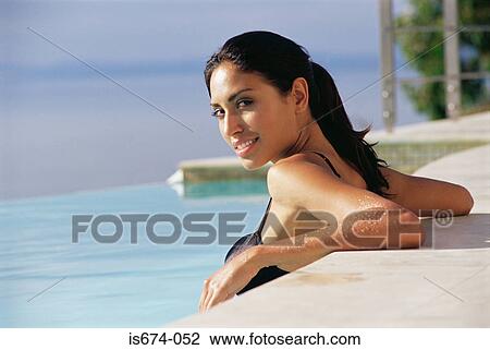 Stock Image - Woman resting on the edge of swimming pool. Fotosearch