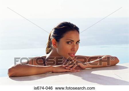 Stock Photograph - Woman resting on the edge of swimming pool. Fotosearch