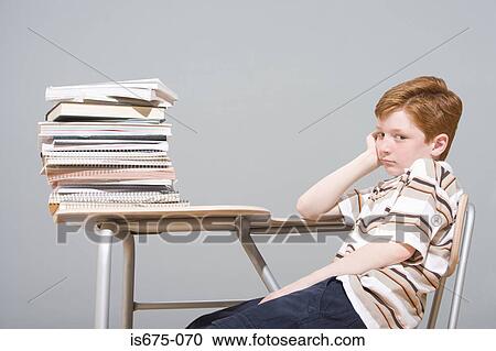 Stock Image - Bored boy sitting at his desk. Fotosearch