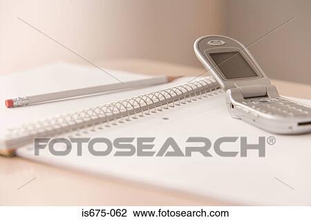 Stock Image - Mobile phone and notepad on a desk. Fotosearch