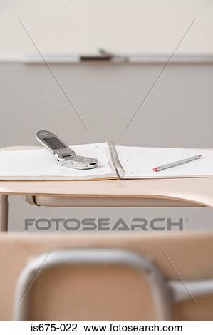 Stock Image - Mobile phone on a classroom desk. Fotosearch