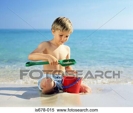 Stock Photography - Boy playing with wet sand. Fotosearch