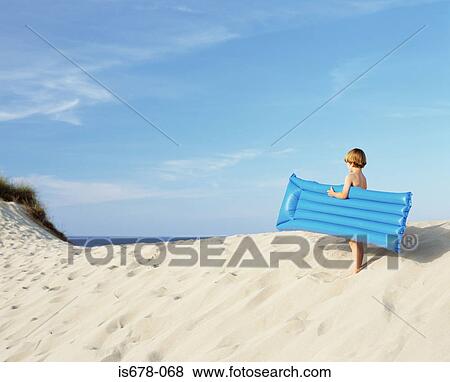 Boy with inflatable on edge of sand dune View Large Photo Image Stock Photo - Boy with inflatable on edge of sand dune. Fotosearch